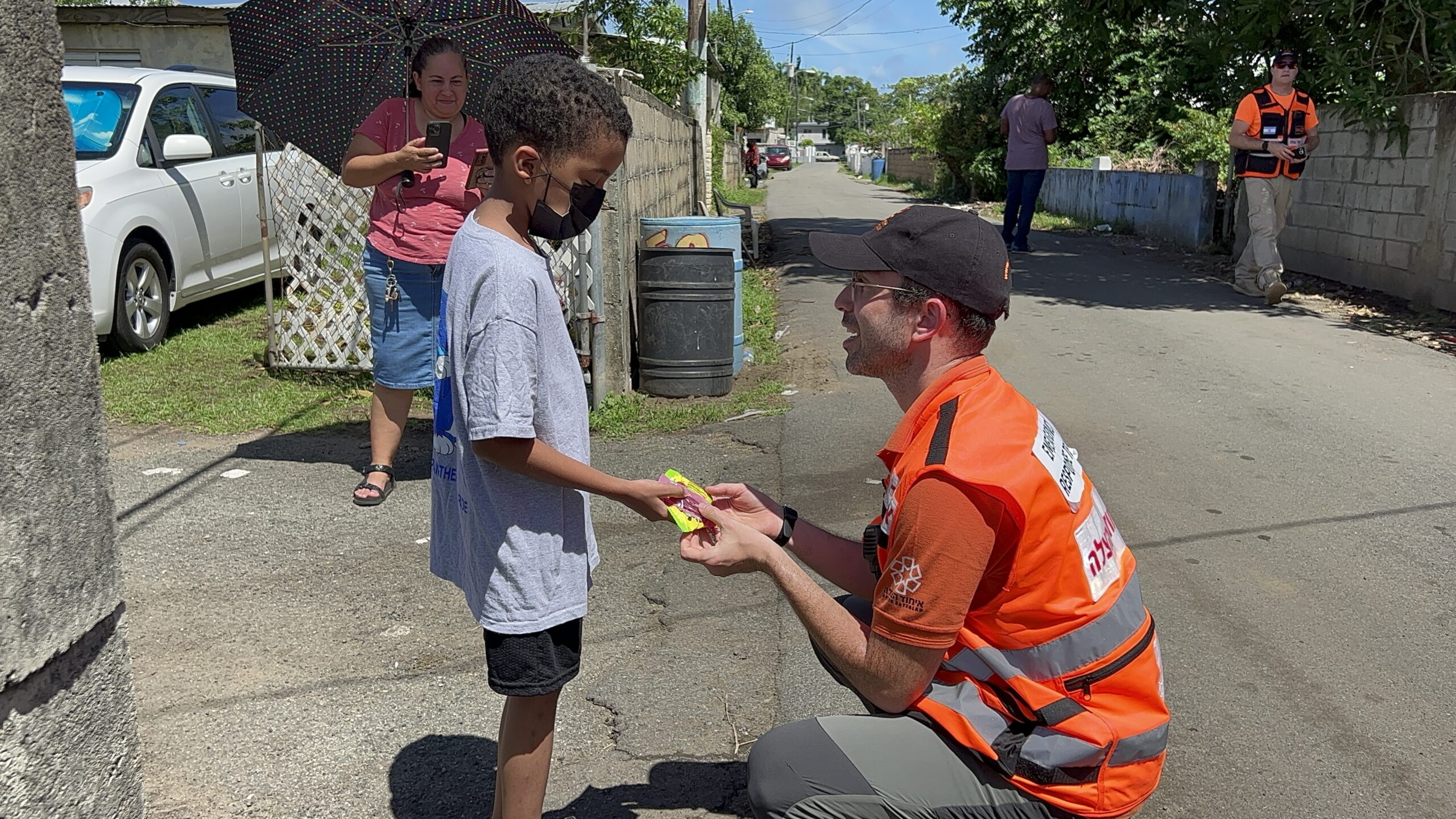 Avishai handing a candy to a young boy in Anasco Puerto Rico 1 scaled 2