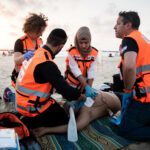 Four medics giving cpr on beach